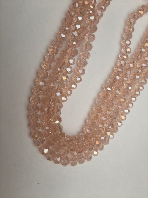 חרוזי קריסטל צ'כיה בצבע ורוד בהיר שקוף, בצורת רונדל מחורץ עם גוון «בנזין», קוטר 8×6 מ״מ ±, אורך 39 מ״מ ± על חוט