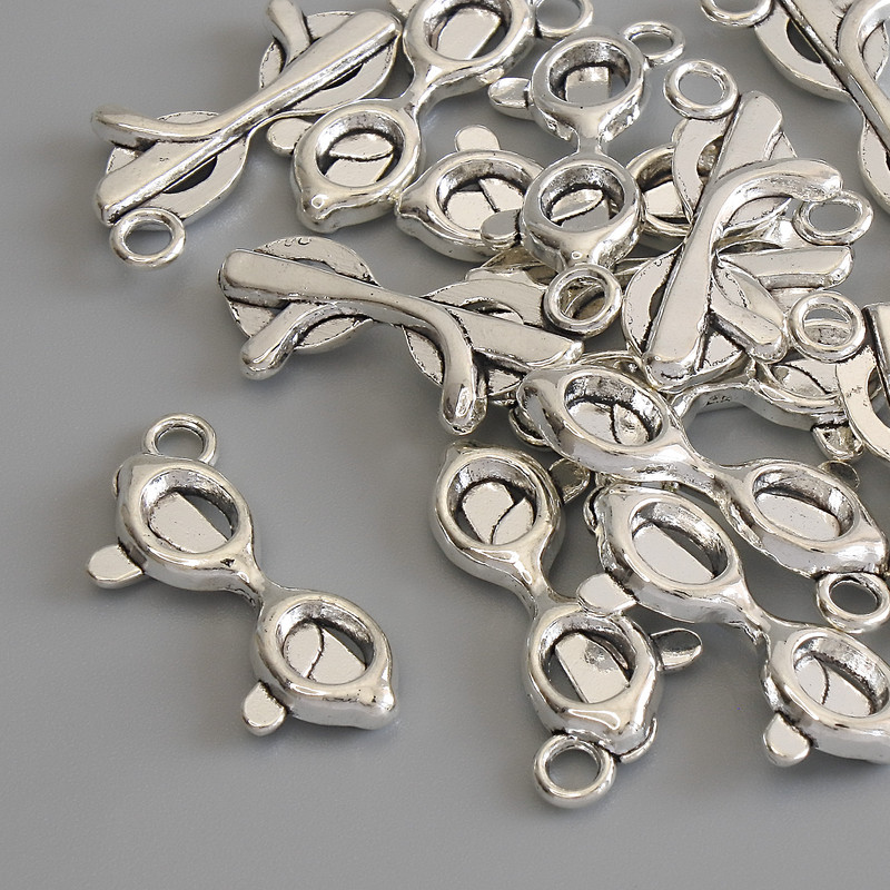 תליון «משקפיים» בצבע מתכת כסופה, קוטר 23×9 מ״מ ± אריזה 15 יחידות