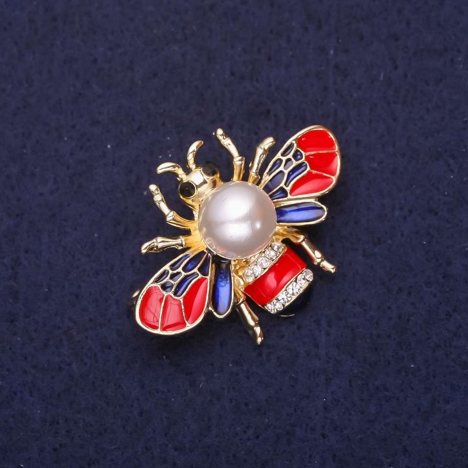 סיכת דבורה עם חרוז פניני, אבני סטרז, אמייל, בצבעים אדום, כחול ולבן, 35×25 מ״מ, מתכת בצבע זהוב